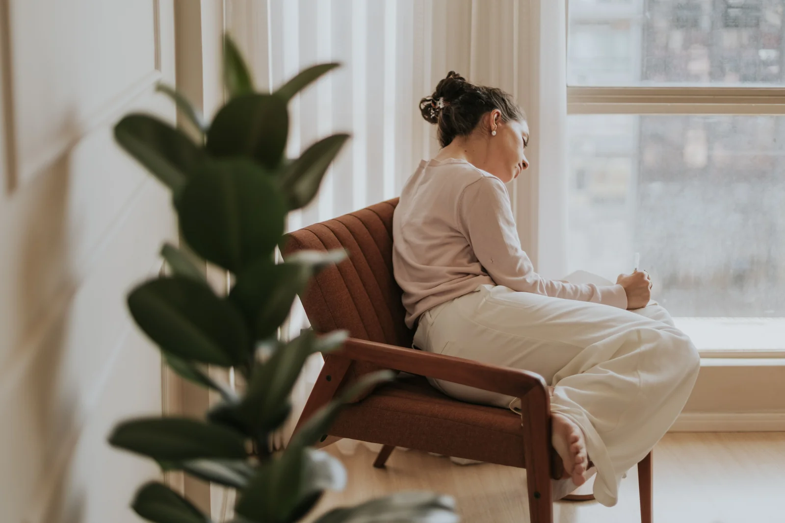 A woman sitting quietly by a window, deep in thought