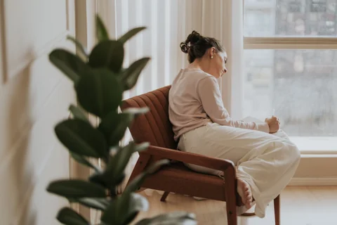 A woman sitting quietly by a window, deep in thought