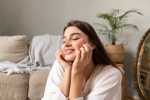 A woman smiling in a moment of quiet self-care at home